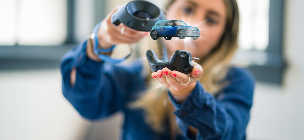 A woman interacs with a miniature car in augmented reality.